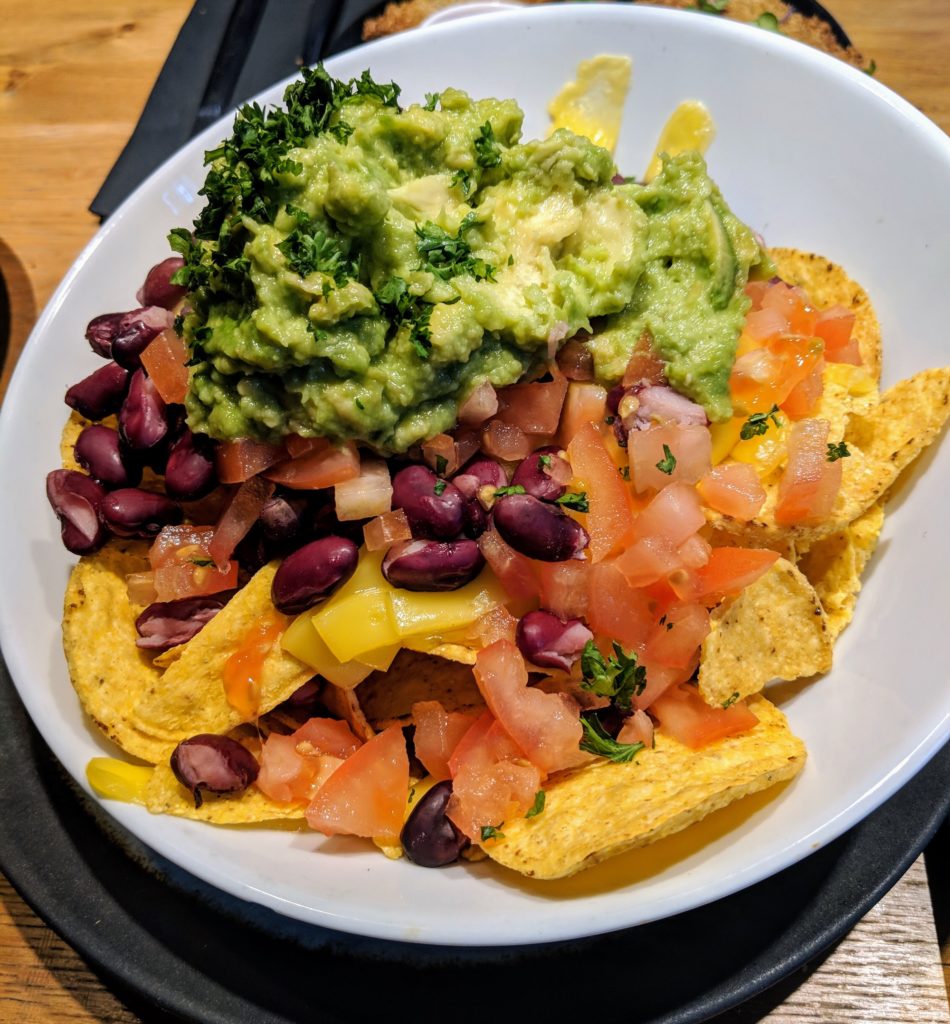 loaded vegan nachos with queso, beans, tomatoes, and guacamole at the meatless district in amsterdam