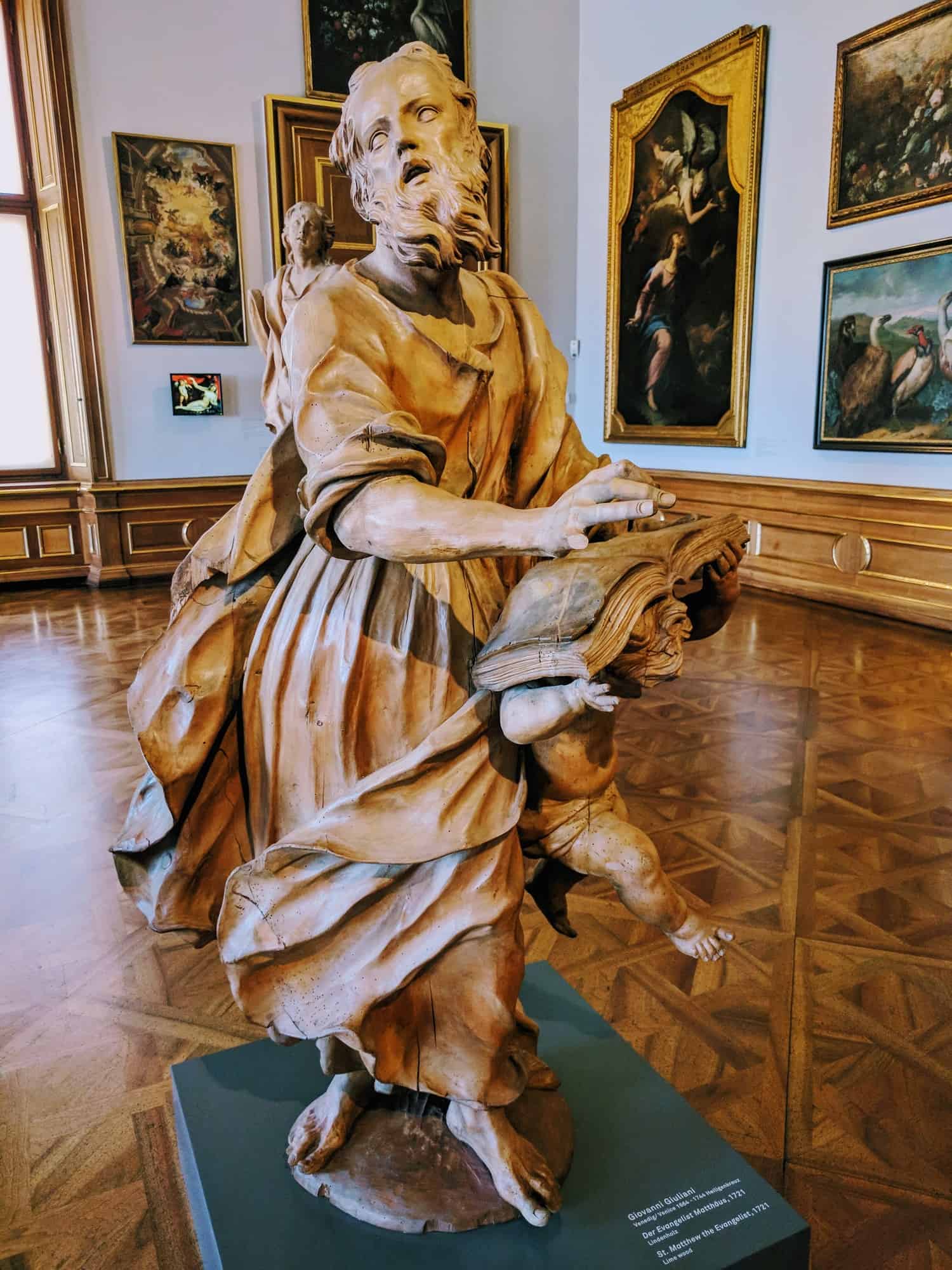 light brown sculpture of a man drapped in cloth, running with his mouth open in the belvedere vienna