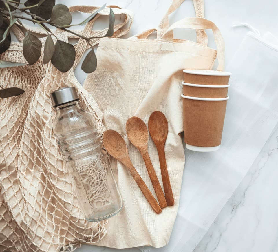 a variety of zero waste products for the home on a marble background with produce and cloth bags