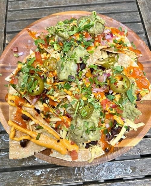 a large round plate filled with vegan nachos and covered in guacamole in philadelphia