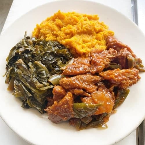 large white plate filled with vegan soul food sides including collard greens, sweet potatoes in philadelphia