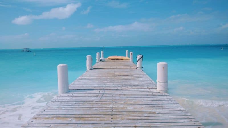 a wood pier that leads into the light blue ocean on grace bay in the turks and caicos