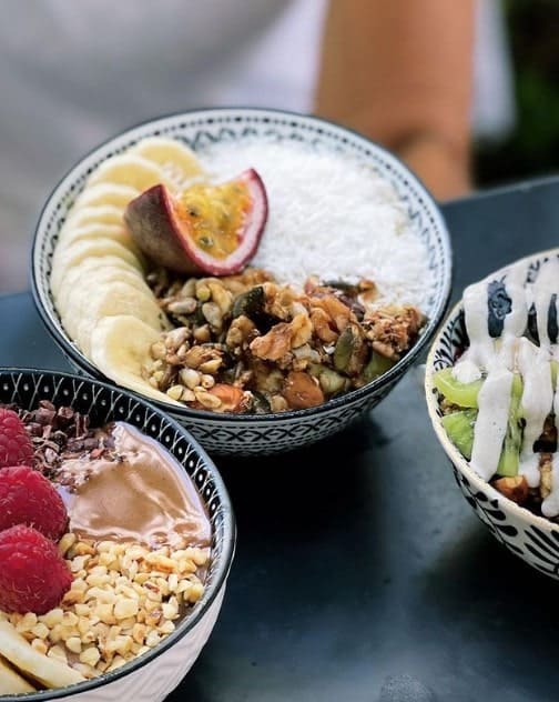 three bowls in a triangle filled with fresh fruit, granola, coconut at simply raw in vienna