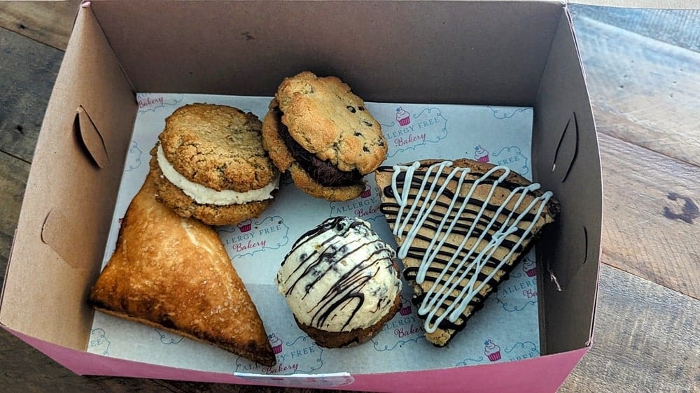 a paper box filled with vegan cookies, cupcake, cherry turnover, and a brookie from allergy free bakery in detroit