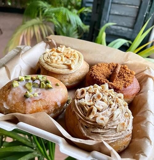 a box with four vegan donuts topped with pistachios, and butter cream at la areca in barcelona
