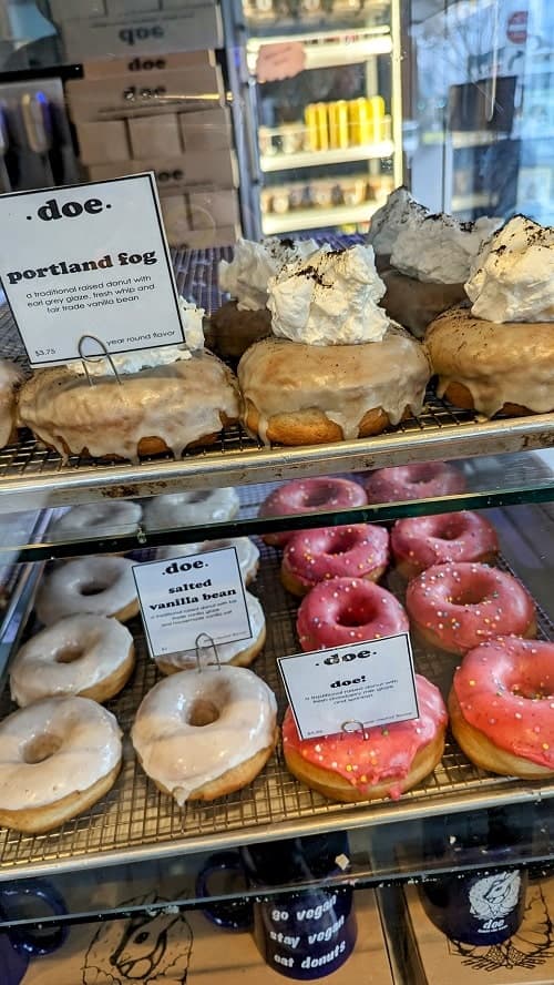 two rows of vegan donuts covered in bright pink icing and white icing at doe donuts in portland