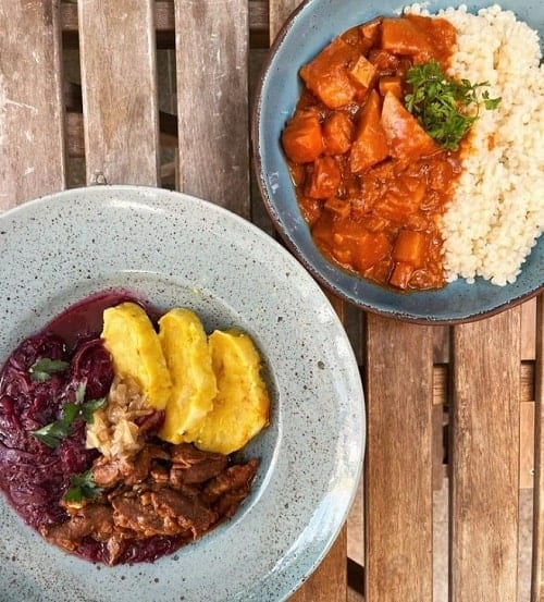 two light gray bowls filled with vegan curry on a wood table in prague