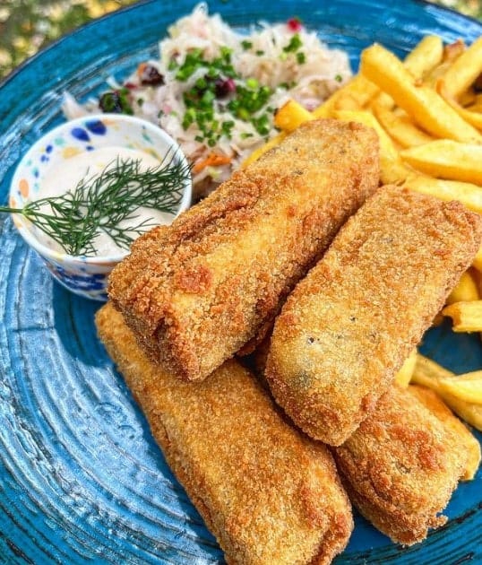 a plate of golden fried vegan fish sticks and fries on a blue plate from lokal in warsaw