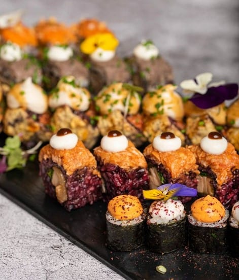 a variety of vegan sushi rolls with colored rice and toppings in barcelona