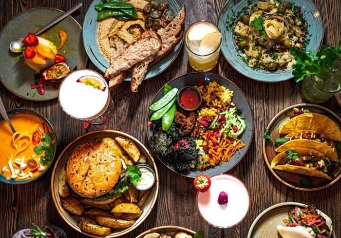 a gorgeous spread of vegan dishes white include a burger, pasta, salad at the botanist in warsaw