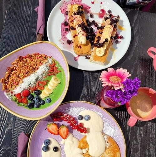 three bowls filled with vegan pancakes and a green smoothie bowl in munich