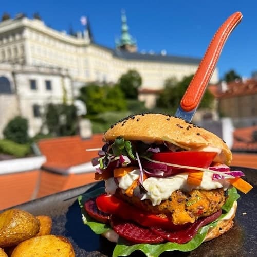 vegan burger with a giant knife sticking in the top in front of old buildings in prague