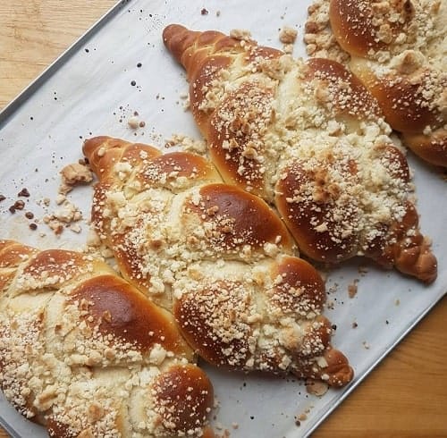 four golden freshly baked rolls of challah bread on a white tray in krakow