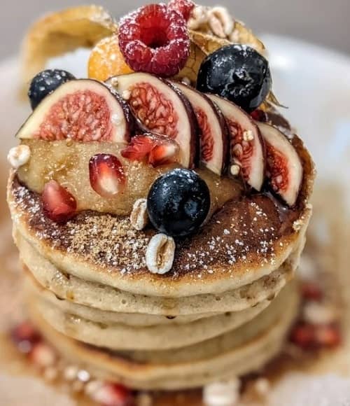 stack of golden vegan pancakes topped with figs and berries at geh veg in berlin