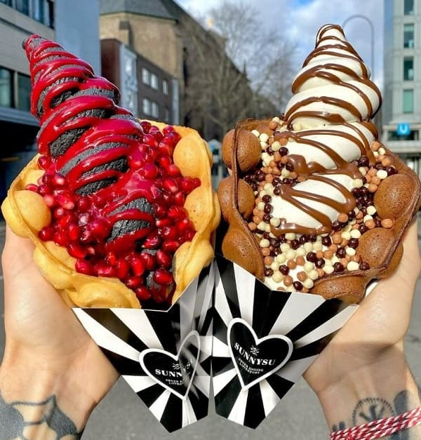 two colorful vegan bubble waffle cones filled with black and vanilla soft serve at sunnyu in cologne