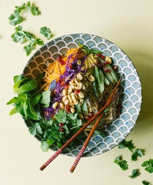 a colorful vegan thai salad with two chopsticks on a green table from veganees in amsterdam
