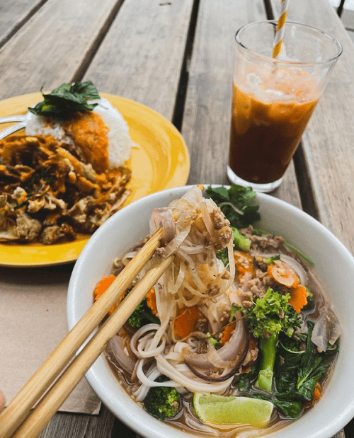 bowl of vegan thai noodles with chopsticks on a wooden table in seattle