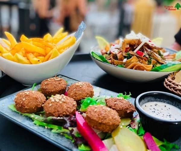a vegan spread of crispy brown falafel, a bowl of golden french fries and a salad in the background at el rincon de beruit in seville