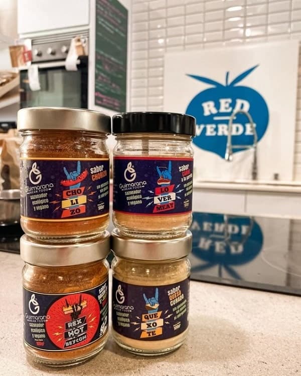 four jars of vegan sauces stacked on top of each other in front of a red verde market sign in seville