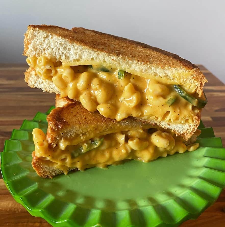 vegan grilled cheese stuffed with mac n cheese cut in half on a green plate at space cat v stro in ferndale