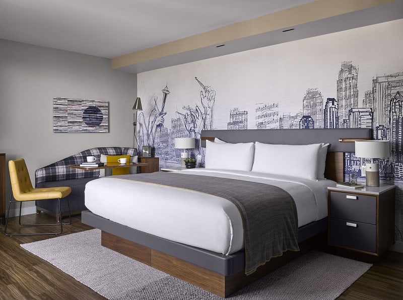modern guestroom with white and gray mural behind a king bed with white and gray linen at the sound hotel in seattle