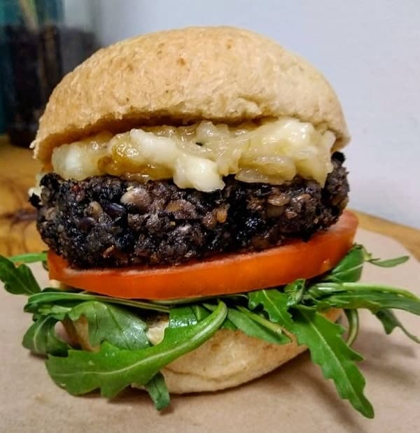 large vegan black bean burger with cheese, tomato, and arugula at vegani in seville 