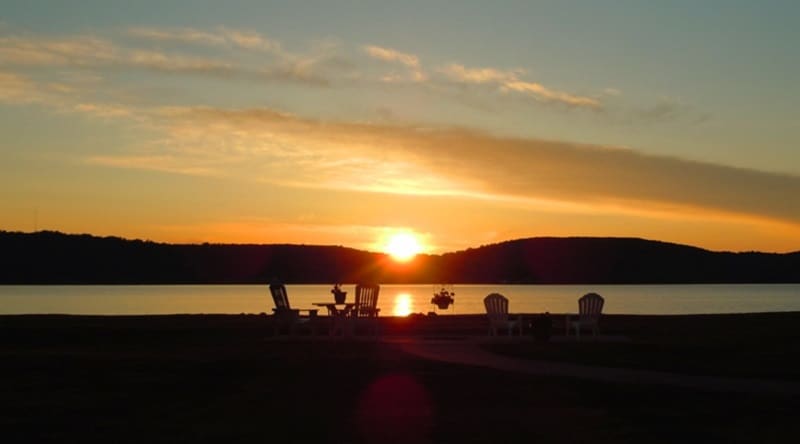 the outdoor sitting area at the beach inn motel in munising with an orange colored sunset