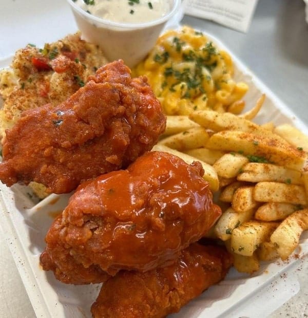 carry out container filled with vegan buffalo chicken wings and golden french fries from the vegan mob in san Francisco 