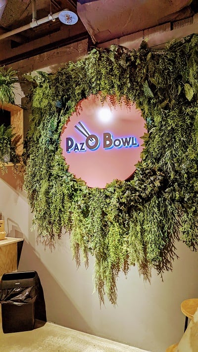 Paz O Bowl shop sign with green vines in Lucerne Train Station