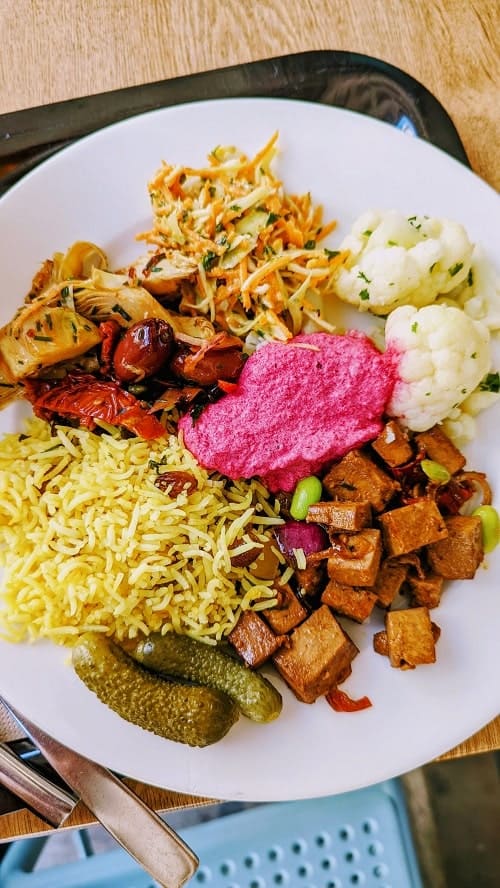 white buffet plate from tonic restaurant with pickles, tofu, rice, pink beet hummus and cauliflower in geneva