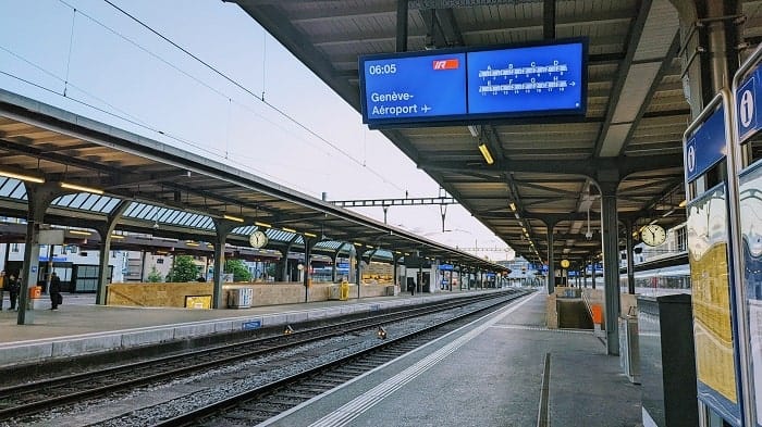 geneva central train station standing at a platform with an electronic sign showing the next train the the geneva airport