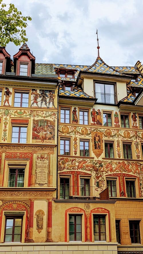 Artwork on the front of medieval buildings with colored tiled roofs in Lucerne