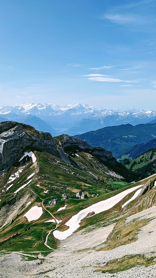 partly cloudy views on mount pilatus, green mountain in the foreground and hazy views of the alps in the background