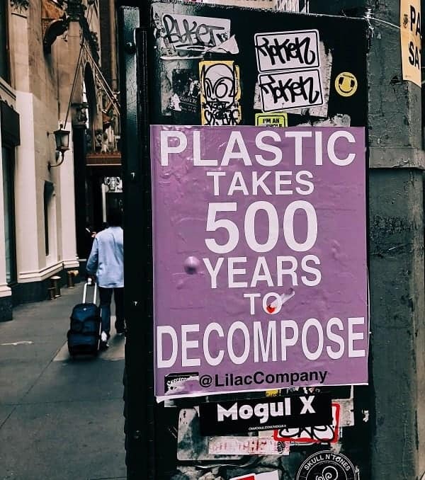 a purple sign on a street post that says: plastic takes 500 years to decompose 