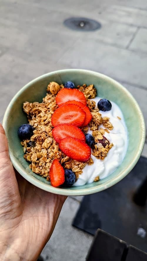 vegan granola bowl with red strawberries, blueberries, and white coconut yogurt from ou bien encore in geneva