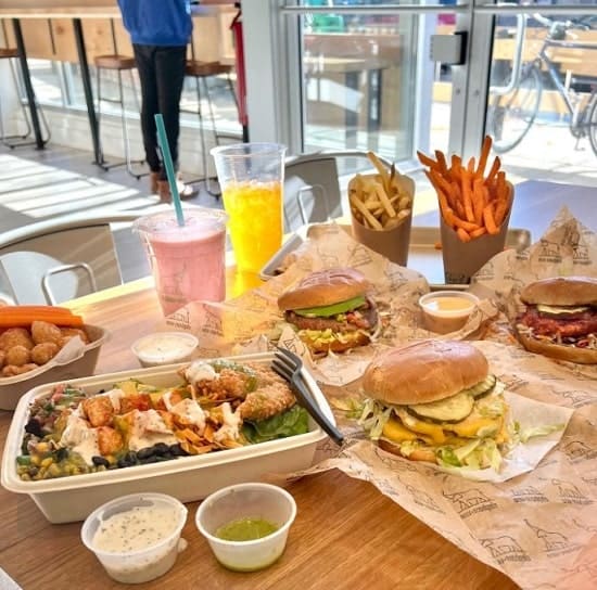 a table filled with vegan burgers, loaded french fries, and milkshakes at elephant + vine in chicago