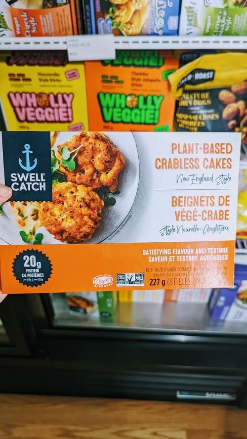 a box of swell catch plant based crab cakes held in front of the freezer section inside of good rebel vegan provisions in toronto