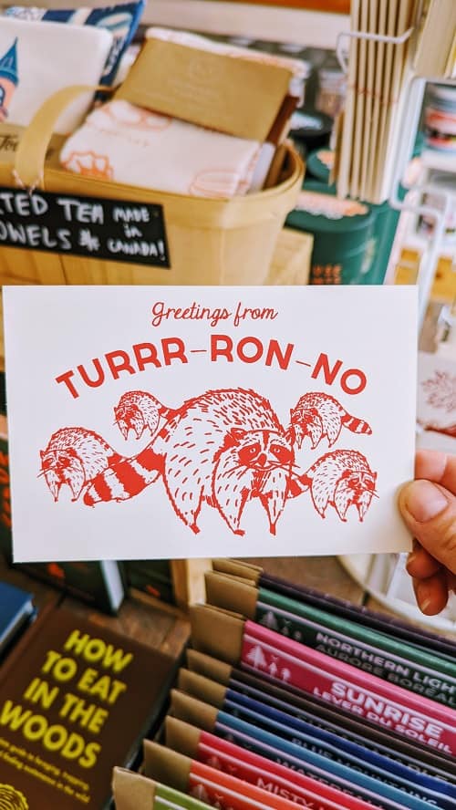 greetings from Toronto spelled TURR-RON-NO with drawings of raccoons in red
