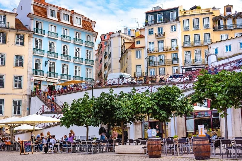 lisbon cafes surrounded by colorful buildings and a stairway that leads to an overlook