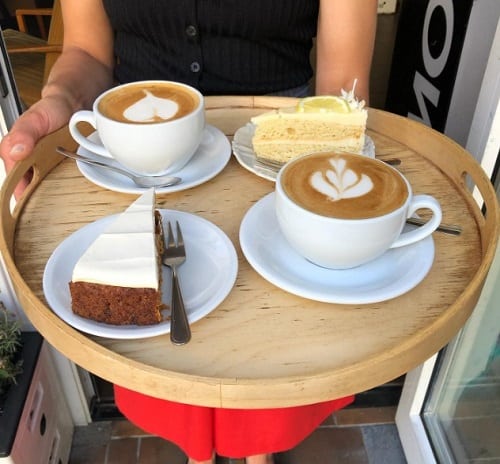 no milk today vegan cafe serving two hot coffee drinks along with vegan cakes on a serving tray in berlin