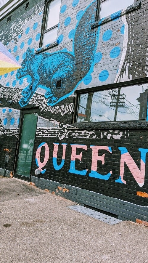 queen street mural with a black and blue squirrel shooting a rainbow from his eyes