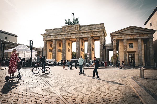 brandenburg gate with people walking and riding bikes at dusk