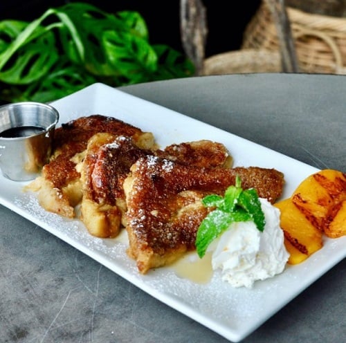 three slices of golden vegan french toast with whipped cream and grilled peaches from spirit elephant in chicago