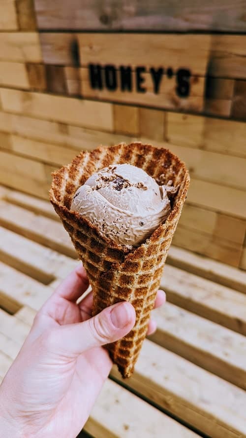 vegan coffee chip ice cream in a gluten free waffle cone on the outdoor patio of honeys plant based ice cream in toronto