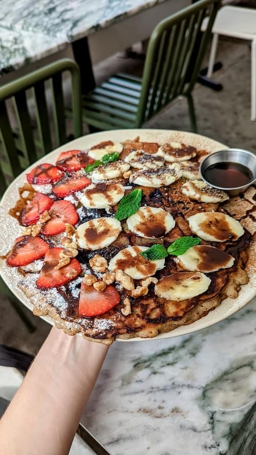 vegan pancakes covered in bananas, strawberries, walnuts, and chocolate sauce from hello 123 in toronto