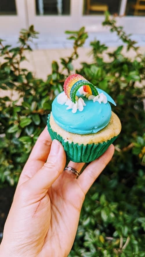 vegan gluten free vanilla pride cupcake with blue frosting and a gummi rainbow at sticky fingers washington dc