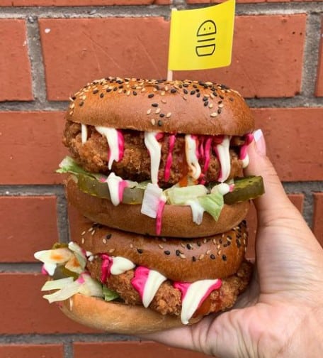 two giant vegan chicken sandwiches stacked on top of each other and dropping with pink and white sauces from v face in dublin