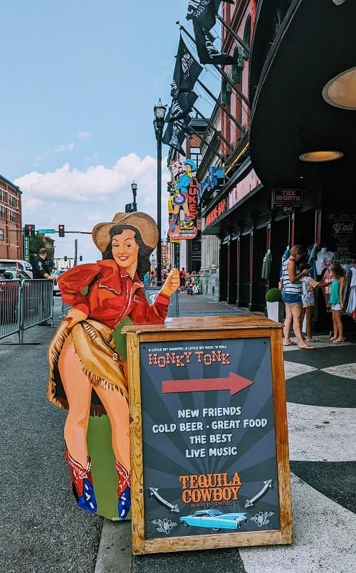cartoon cowgirl standing next to a honky tonk sign in downtown nashville