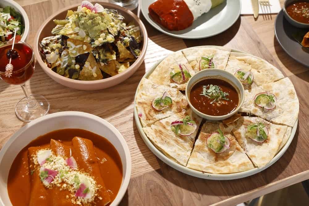 an incredible spread of vegan mexican dishes spread across a wood table at jajaja in miami