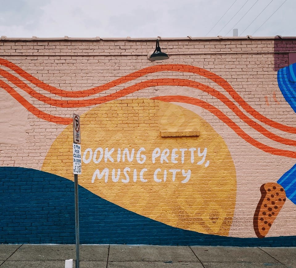 pink and yellow mural in nashville that says looking pretty music city